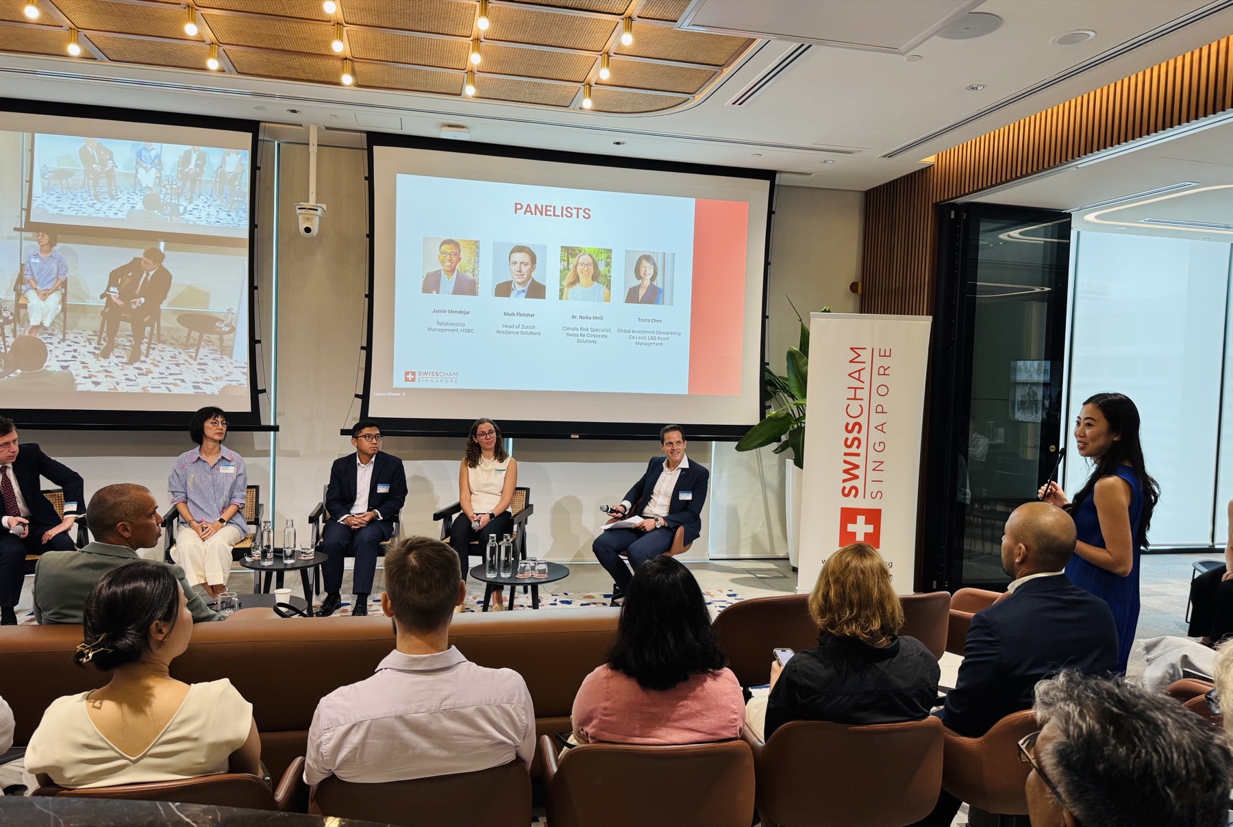 A panel on stage beside a SwissCham Singapore banner